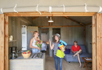 Binnenbeeld van mensen in een comfortabele hut bij Hut Lodge CONFORT op Flower Camping Le Conleau, Frankrijk.