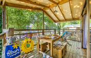 Terrasse der Hut lodge Cosyflower PREMIUM mit Frühstückstisch, Spielzeug und Waldblick auf Campingplatz.