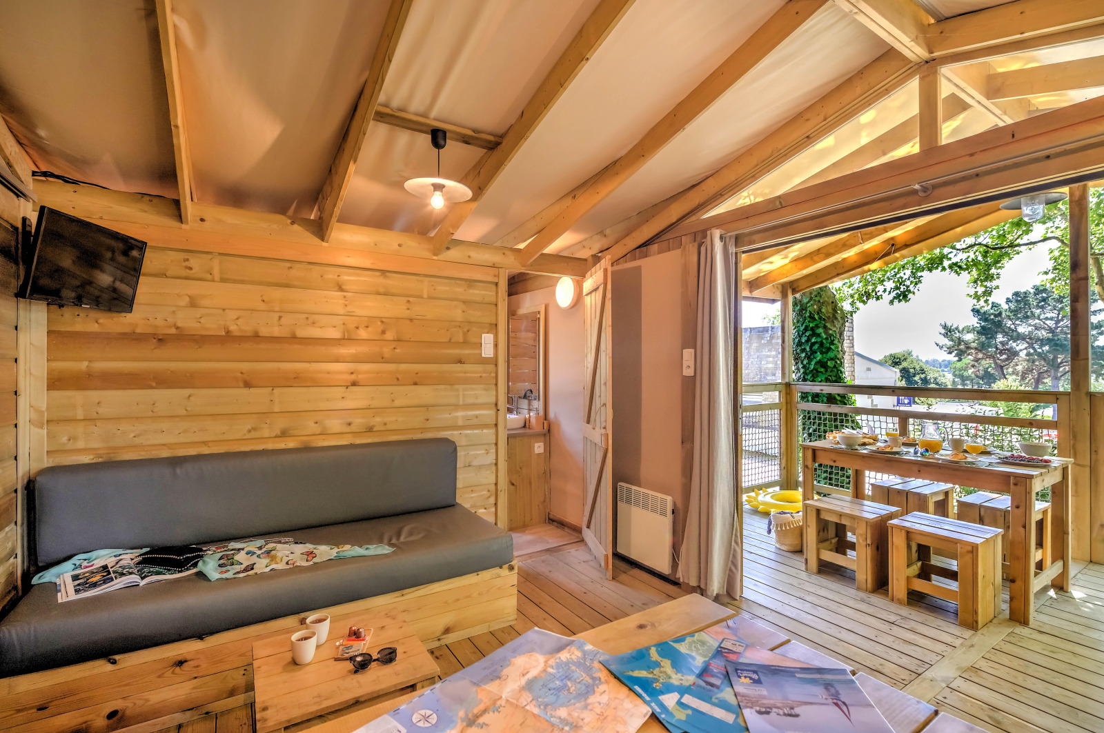 Gezellig houten hutinterieur met open terras en eetgedeelte bij Flower Camping Le Conleau in Frankrijk.