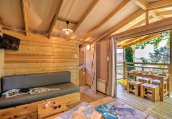 Gemütliches Blockhütteninterieur mit offener Terrasse und Holzmöbeln im Flower Camping Le Conleau, Frankreich.