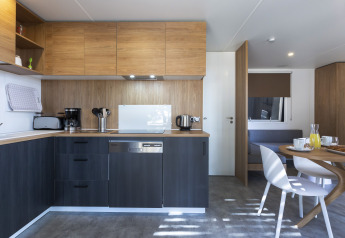 Cucina moderna e zona pranzo in un alloggio glamping con mobili in legno e stoviglie.