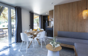 Modern glamping accommodation interior with dining area, kitchenette, stylish decor, and view outside.
