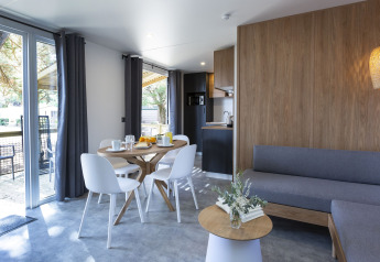 Modern glamping accommodation interior with dining area, kitchenette, stylish decor, and view outside.