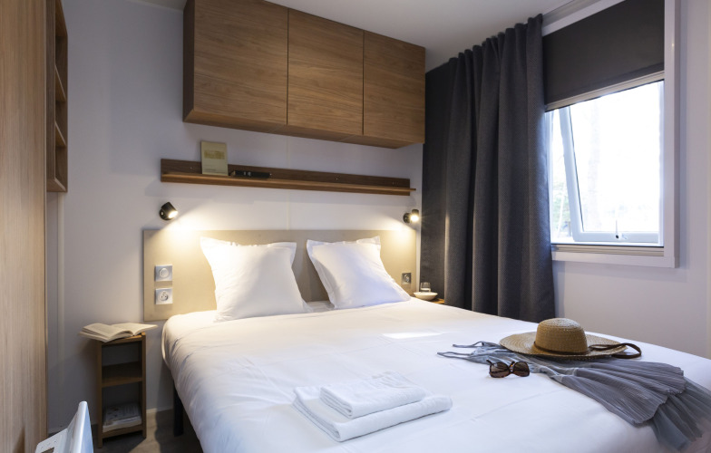 Modernes Glamping-Zimmer mit gemütlichem Doppelbett, stilvoller Einrichtung und Fenster mit Tageslicht.