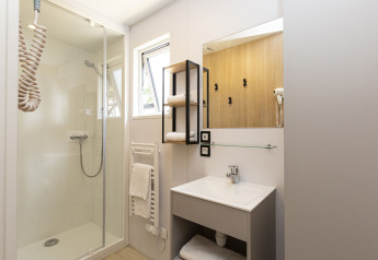 Modernes Badezimmer in einer Glamping-Unterkunft, mit Dusche, Waschbecken, Spiegel und Handtüchern.