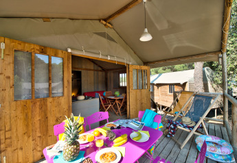Safari-Zelt Hut Lodge Comfort mit bunter Terrasse und Frühstück bei Flower Camping Le Bois d’Amour in Frankreich.