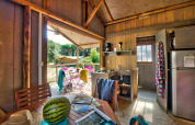 Intérieur d'une tente safari confortable avec panneaux en bois, cuisine équipée et terrasse en camping en France.