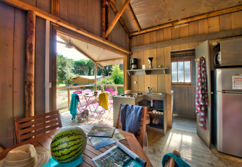 Intérieur d'une tente safari confortable avec panneaux en bois, cuisine équipée et terrasse en camping en France.