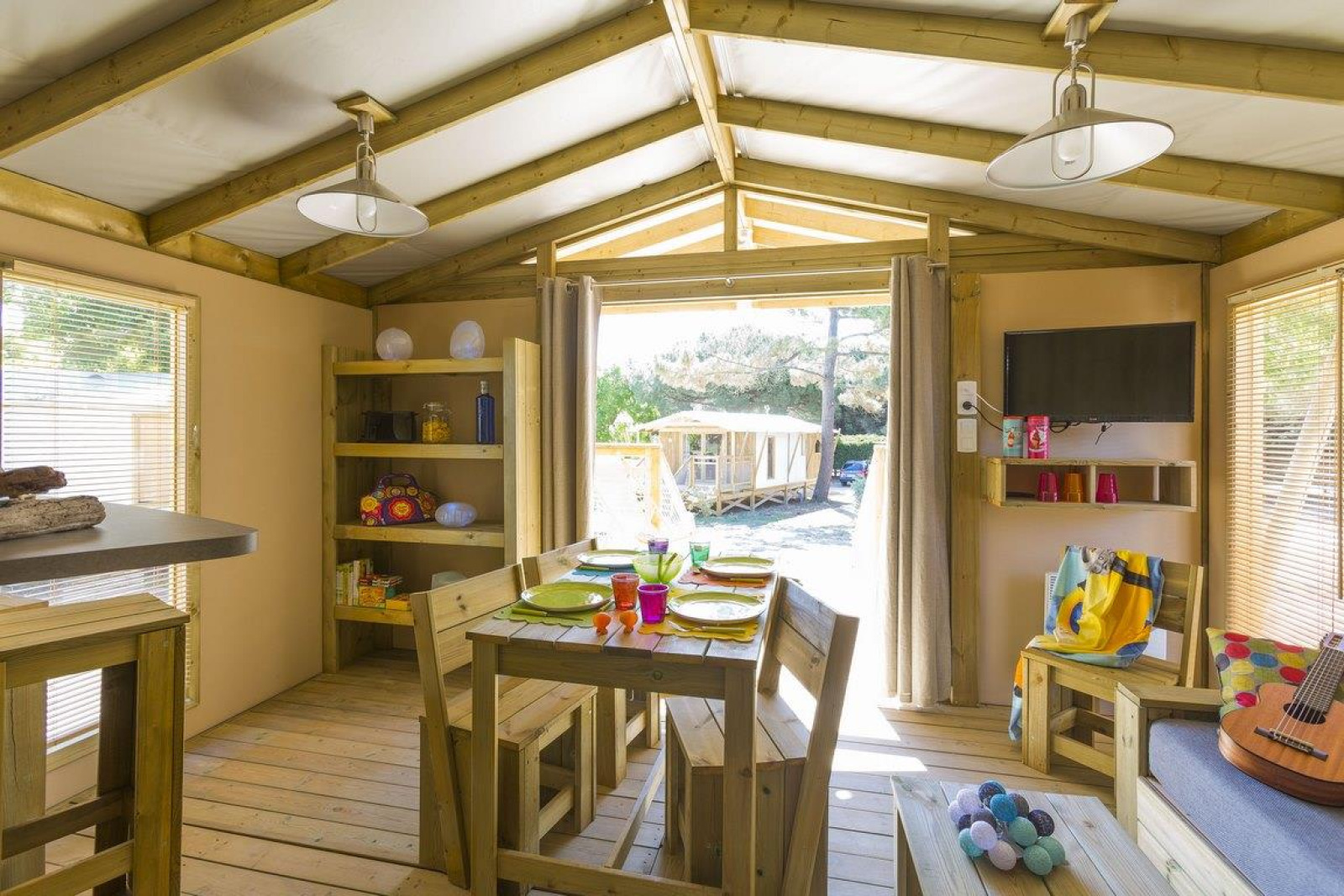 Binnenaanzicht van een safaritent bij Flower Camping Le Bois d'Amour in Frankrijk, met houten meubels en zonlicht.