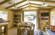 Vista interior de una tienda safari en Flower Camping Le Bois d'Amour, Francia, con muebles de madera y luz natural.