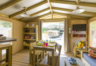 Vista interna di una tenda safari a Flower Camping Le Bois d'Amour in Francia, con arredi in legno e luce naturale.