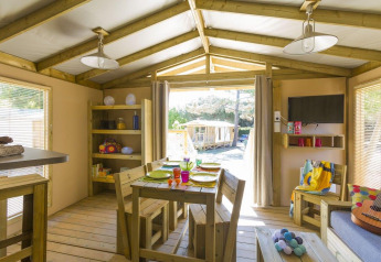 Innenaufnahme eines Safari-Zeltes im Flower Camping Le Bois d'Amour in Frankreich mit Holzmöbeln und Wohnzimmer.