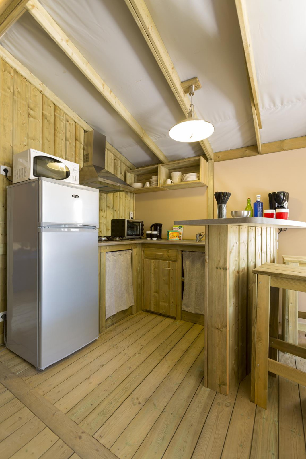 Houten keuken met moderne apparatuur in een safaritent bij Hut Sweetflower Premium, Flower Camping Le Bois d'Amour, Frankrijk.