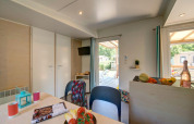 Moderne glampingaccommodatie met lichte eethoek, keuken en toegang tot zonnig terras buiten.