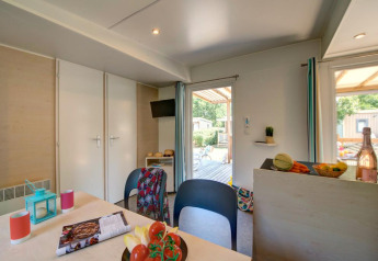Moderne glampingaccommodatie met een lichte eetruimte, keukentje en toegang tot een zonnig terras.