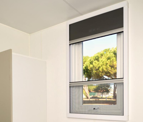 Window in Homeflower Premium at Flower Camping Le Bois d'Amour, France, with view of trees outside.