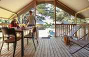 Famille prenant le petit déjeuner dans une tente Lodge Confort au Camping Demoiselles Plage, France, terrasse.