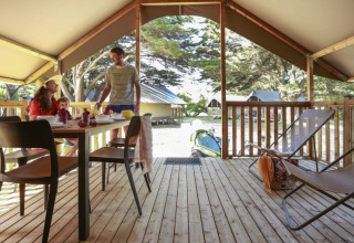 Gezin ontbijt in een safaritent Lodge Confort op Camping Demoiselles Plage, Frankrijk, met houten terras.