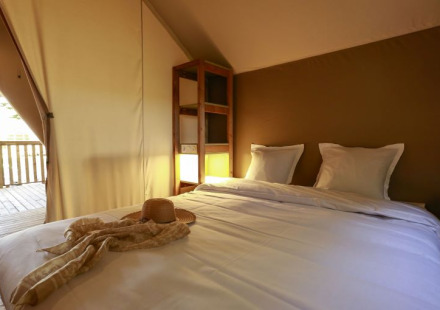 Gezellige slaapkamer in Safari Tent Lodge Confort bij Camping Demoiselles Plage in Frankrijk met licht.