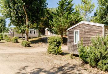 Case mobili Stacaravan Confort al Camping Demoiselles Plage, Francia, circondate da alberi e cespugli al sole.