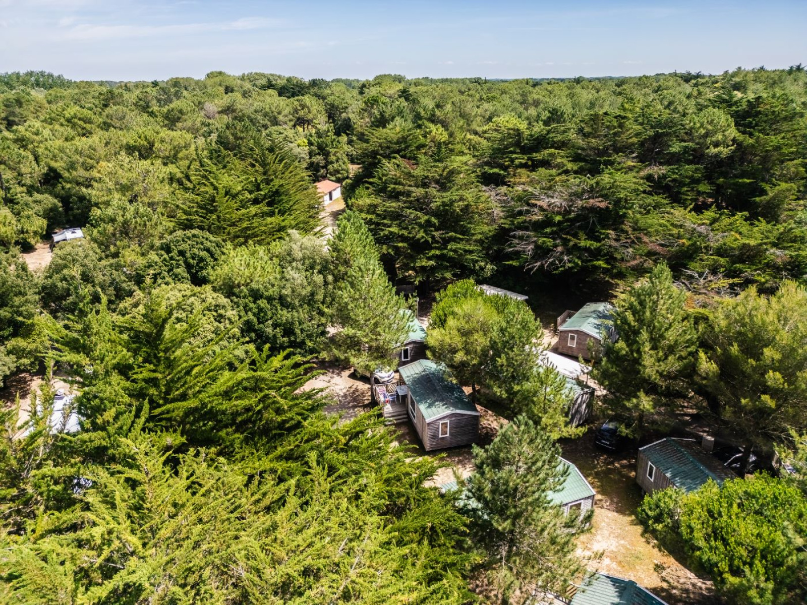 Luchtfoto van Stacaravan Confort huisjes tussen bomen bij Camping Demoiselles Plage in Frankrijk.