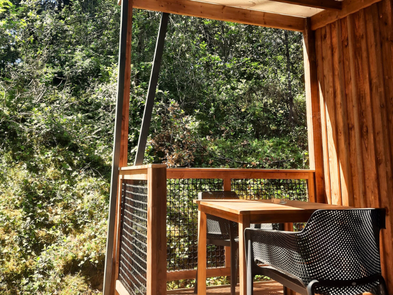 Houten terras met tafel en stoelen bij Chalet Bois Premium op Flower Camping Les Dunes, omgeven door bos.