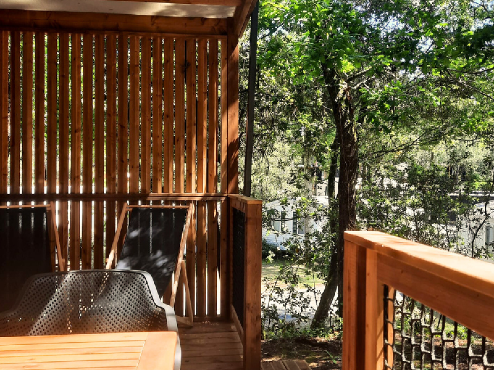 Uitzicht vanaf het houten terras van Chalet Bois Premium bij Flower Camping Les Dunes, omringd door bomen in Frankrijk.