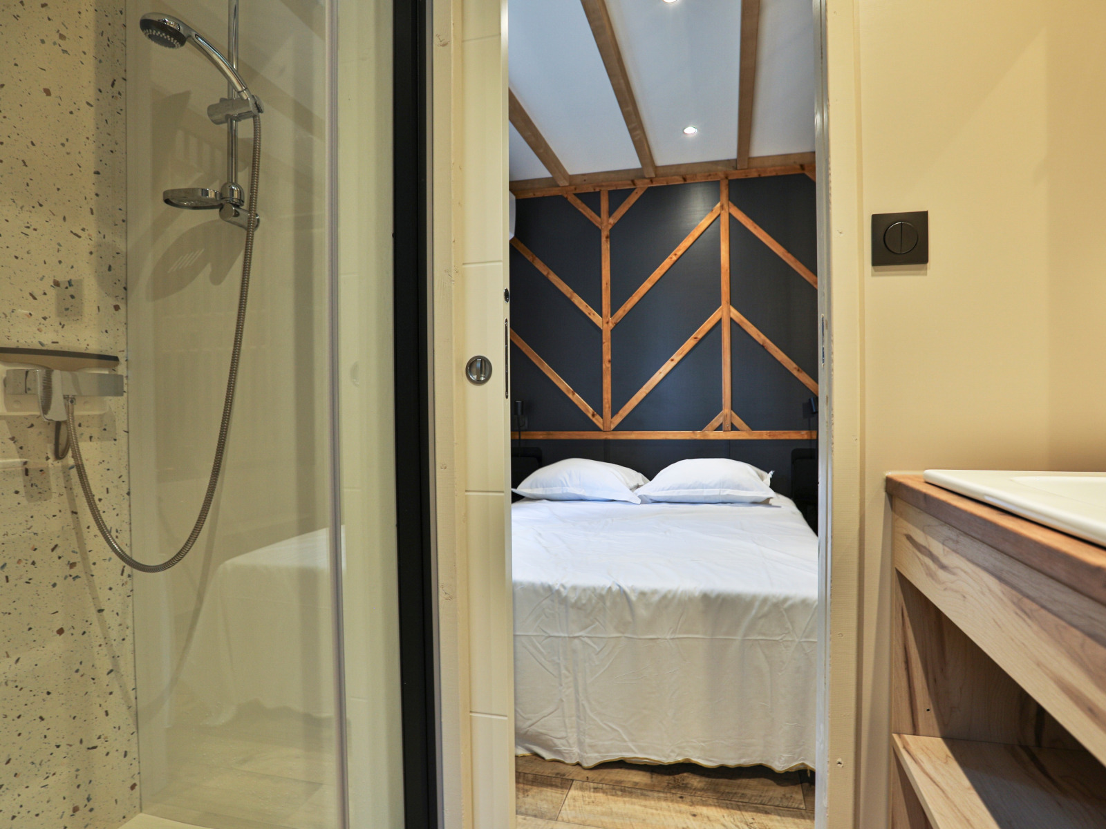 Uitzicht op slaapkamer met moderne douche in Chalet Bois Premium, Flower Camping Les Dunes, Frankrijk.