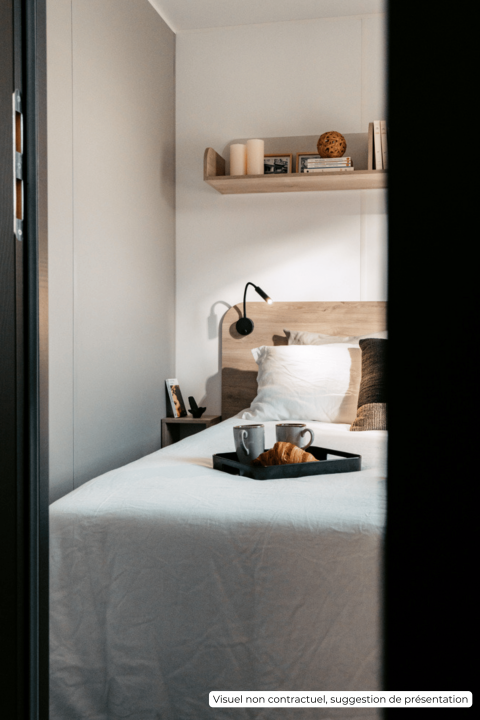 Gezellige slaapkamer met ontbijtplank op bed bij Homeflower Premium 1 kamer in Flower Camping Les Dunes, Frankrijk.