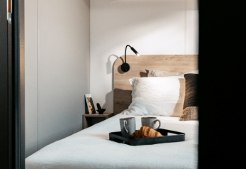 Gezellige slaapkamer met ontbijtplank op bed bij Homeflower Premium 1 kamer in Flower Camping Les Dunes, Frankrijk.