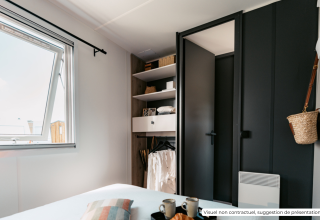 Modern bedroom with black wardrobe, open window, and minimalist decor at Homeflower Premium lodge in France.