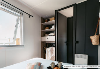 Moderne slaapkamer met zwarte kast en open raam in het Homeflower Premium lodge in Frankrijk.