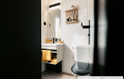 Modern bathroom with white walls, black toilet, sink, and yellow towel at Homeflower Premium lodge in France.