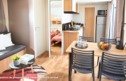 Modernes Glamping-Unterkunft mit Essbereich, Sofa, Küche und Blick auf ein Zimmer mit Etagenbett.