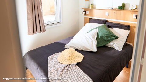 Acogedor dormitorio glamping con cama doble, cojines grandes, ventana, y una decoración moderna.