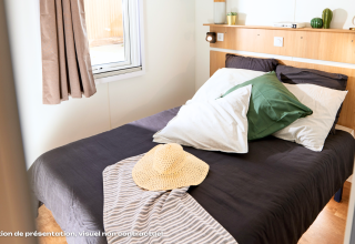 Acogedor dormitorio glamping con cama doble, cojines grandes, ventana, y una decoración moderna.