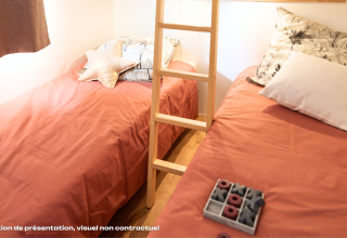 Dos camas individuales con ropa de cama color durazno en un alojamiento glamping acogedor con cojines.