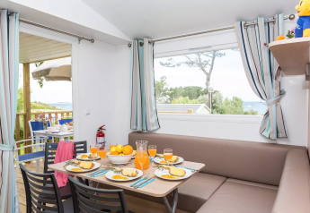 Alloggio glamping luminoso con tavolo da pranzo per quattro, grandi finestre e vista panoramica.