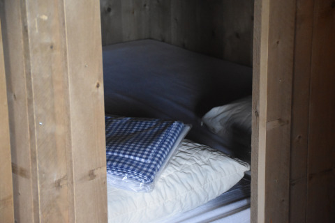 Chambre chaleureuse en bois à Kidz Lodge, Duynpark Het Zwanenwater, Pays-Bas, avec lit, oreiller et couverture.