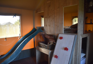 Zona de juegos interior en Kidz Lodge, Duynpark Het Zwanenwater, Países Bajos, con tobogán y pared de escalada.