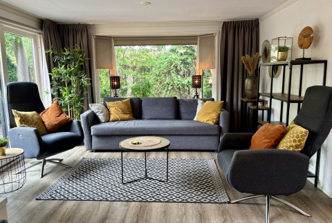 Moderne woonkamer in Cozy Lodge bij Bungalowpark Het Verscholen Dorp, Nederland, met zetels en grote ramen.