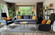 Moderne stue i Cozy Lodge ved Bungalowpark Het Verscholen Dorp, Holland, med sofa, lænestole og store vinduer.