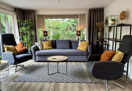Modernes Wohnzimmer im Cozy Lodge im Bungalowpark Het Verscholen Dorp, Niederlande, mit großen Fenstern.