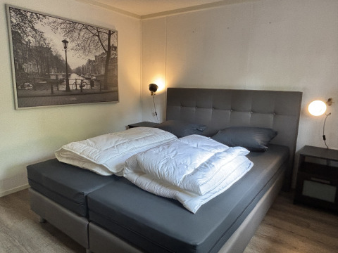 Slaapkamer in Cozy Lodge bij Bungalowpark Het Verscholen Dorp met tweepersoonsbed, nachtkastjes en zwart-wit muurkunst.