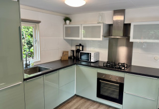 Moderne keuken in Cozy Lodge in Bungalowpark Het Verscholen Dorp, Nederland, met oven en fornuis.