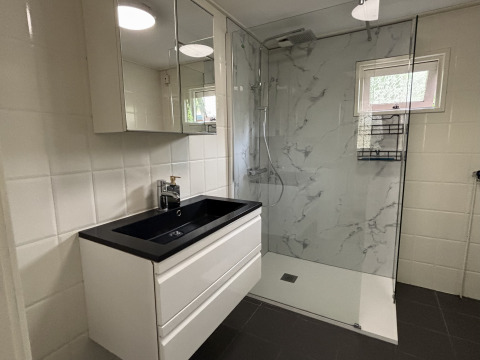 Bagno moderno con lavabo nero, specchio e doccia al Cozy Lodge presso Bungalowpark Het Verscholen Dorp.