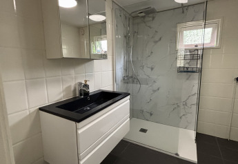 Baño moderno con lavabo negro, armario con espejo y ducha en Cozy Lodge, Bungalowpark Het Verscholen Dorp.