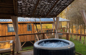 Buitenveranda met bubbelende jacuzzi en zitje bij Charme hut met jacuzzi op Camping Le Périgord, Frankrijk.