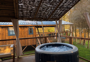 Terraza exterior con jacuzzi burbujeante y asientos en Charme hut met jacuzzi, Camping Le Périgord, Francia.