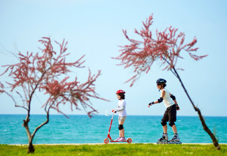 Due bambini con monopattino e pattini a rotelle vicino al mare ad Aminess Planet Camping Sirena, Istria, Croazia.